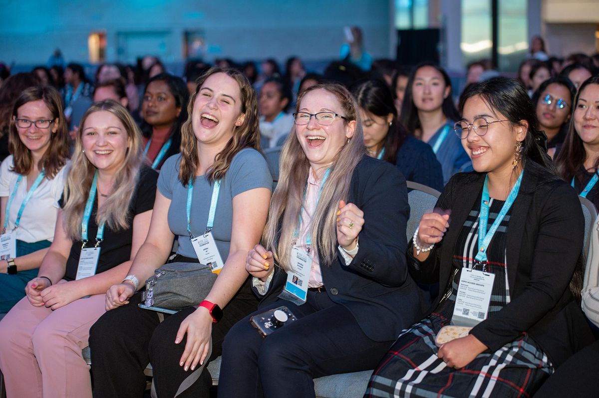 Attendees laughing and reacting during a keynote session at a corporate leadership conference, capturing real audience engagement and connection