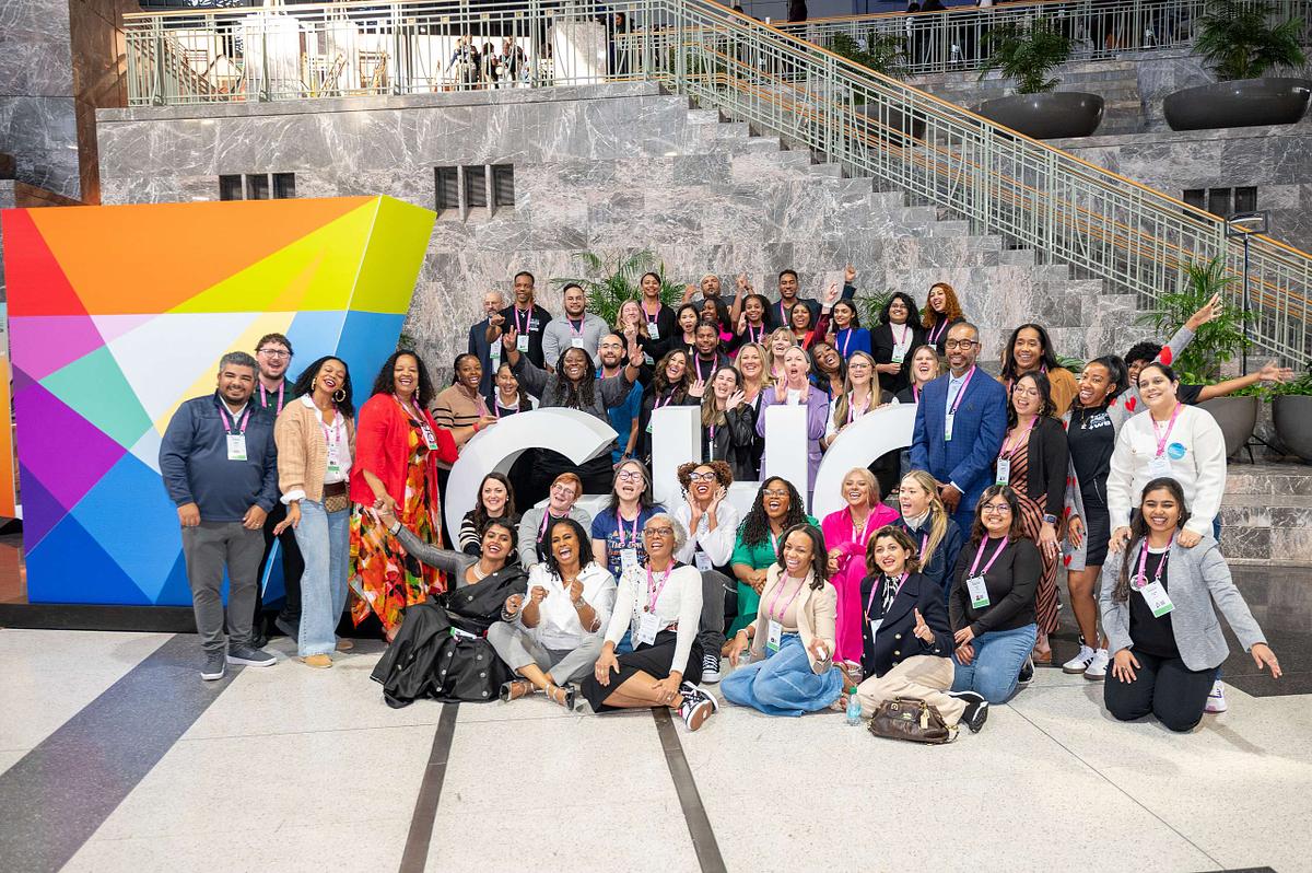 AnitaB.org CEO Brenda Darden Wilkerson poses with the full AnitaB.org team in front of the GHC sign at Grace Hopper Celebration 2024 in Philadelphia.