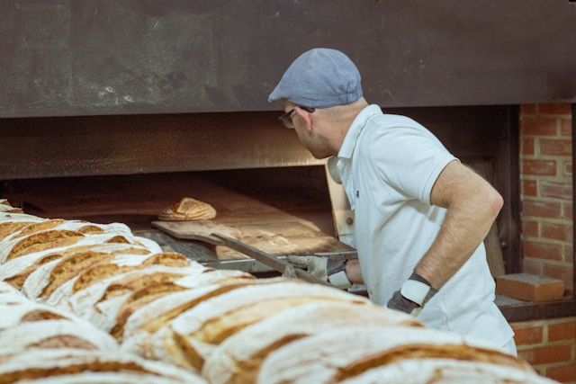 a baker wearing while poloshirt and a cap in a bakery