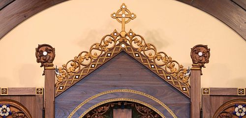 Detail photo of the upper part of the altarpiece showing the crockets, finials, cross, flowers, and nuthatches