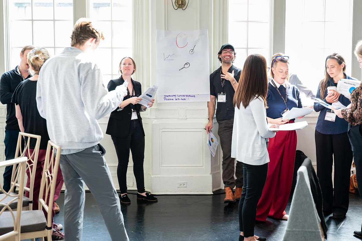 Professionals participating in a workshop session in the Bellevue Rose Garden Room in Philadelphia, gathered around a presentation board during a corporate event