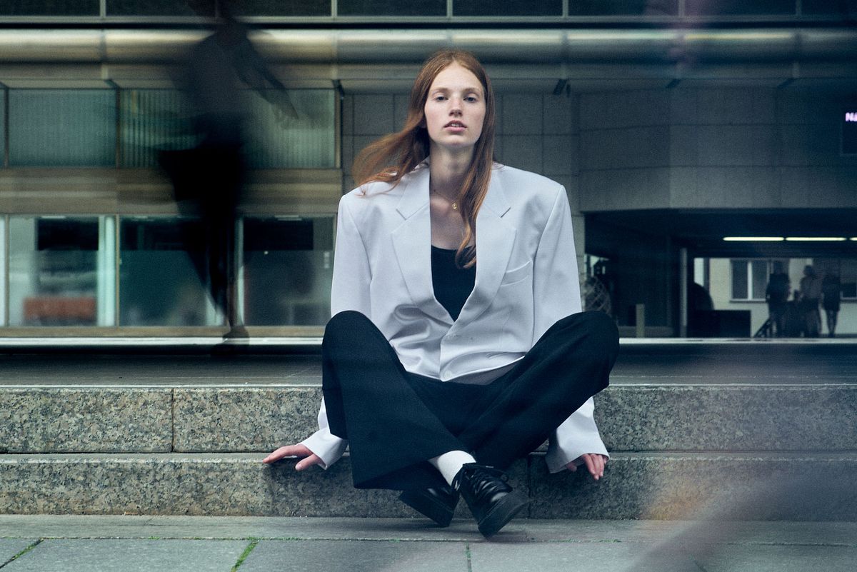 Contemporary fashion portrait of a woman in oversized white blazer in an urban environment with motion blur, Pure Models Prague, by Gabriel Matula.