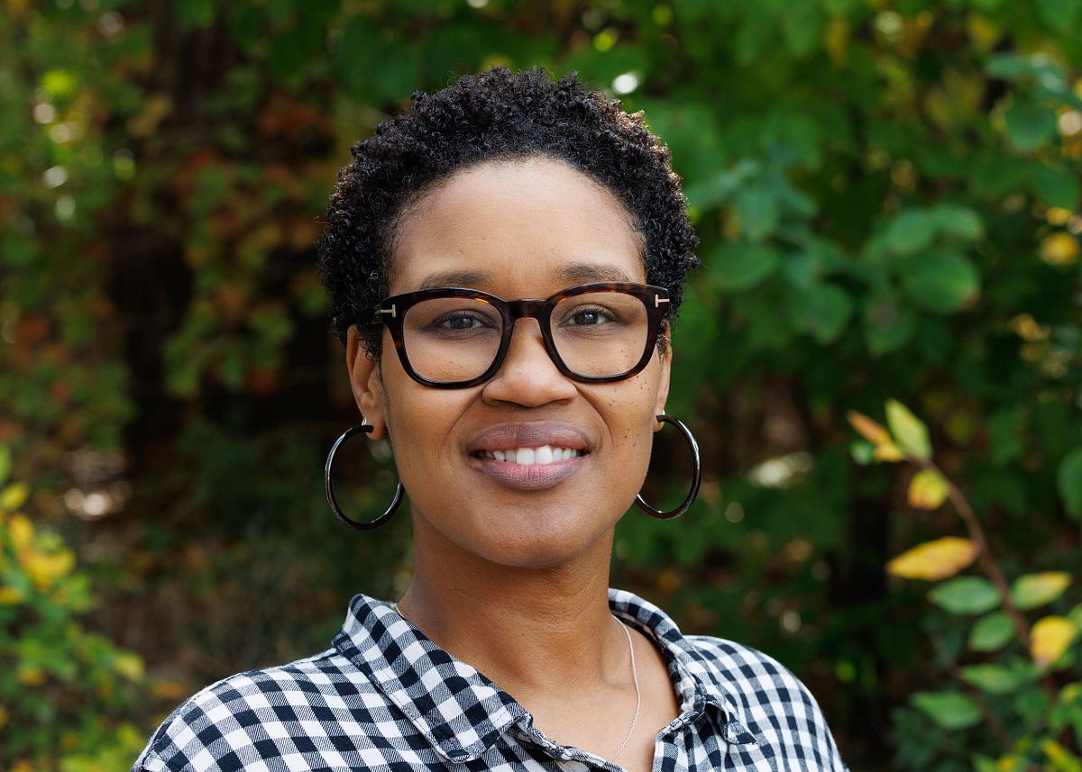A close-up headshot of a woman against a wooded backdrop on UNC's campus in Chapel Hill, NC