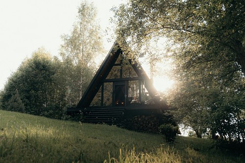 Black A-frame cabin in a quiet green forest in Latvia