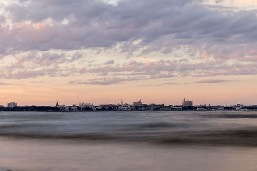Charleston skyline at sunset over gentle harbor waves