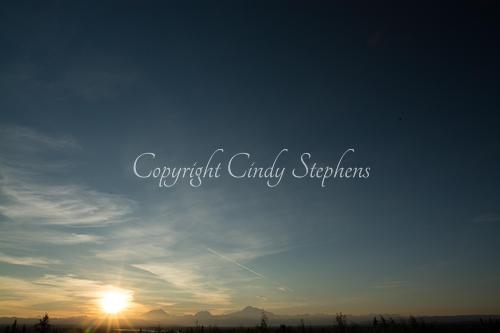 Setting sun against pine trees and mountains in Alaska