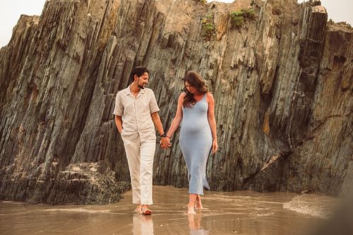 coppia in gravidanza cammina nel bagnasciuga di Masua in Sardegna