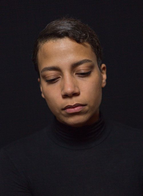 A headshot of a woman in a black turtleneck with her eyes closed.