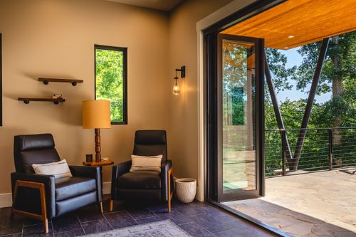 Man cave seating area opening up to covered patio; view of angled posts beyond