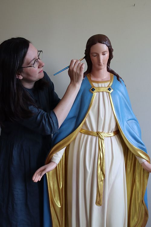 Kelly Baker painting last touches to Blessed Virgin Mary statue restoration