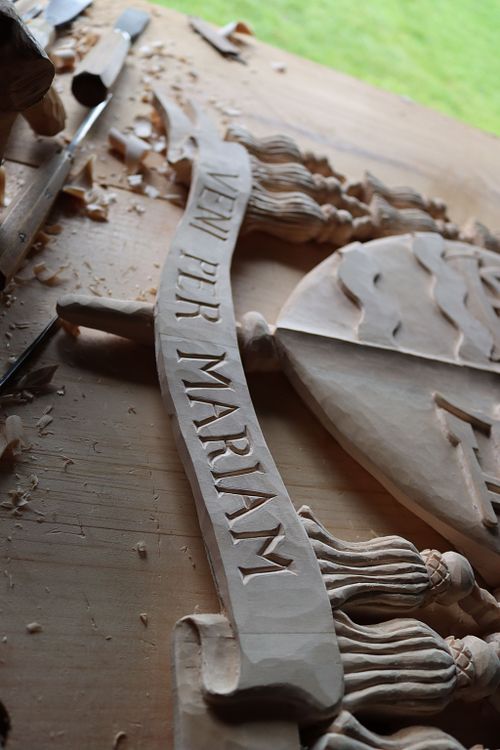 Bishop Fernandes' episcopal motto is carved on the banner below the escutcheon: "Veni per Mariam" which means, "Come through Mary"