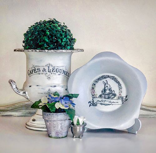Decorative pot with lush greenery and vintage floral plate, perfect for home decor