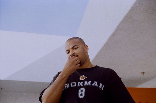 Black man looking down in front of wall