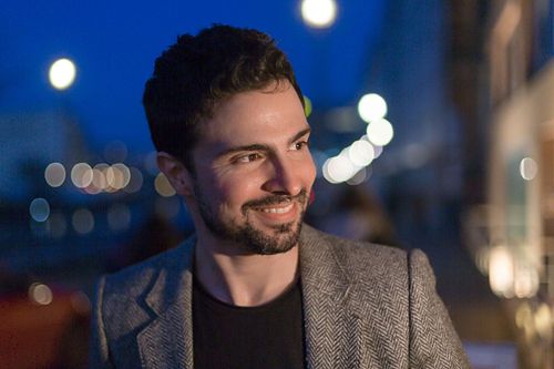 Headshot of Toni Gojanovic in a grey jacket standing in front of a building at night.